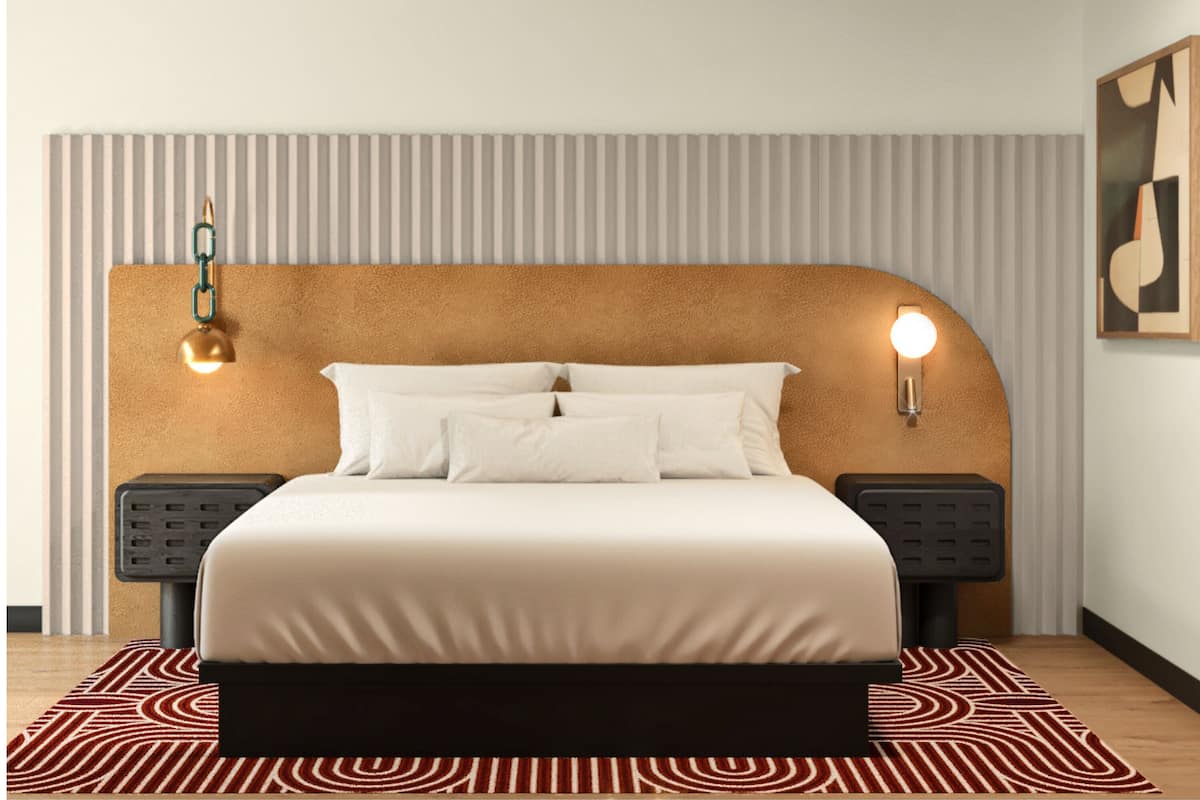 A modern bedroom with a headboard, a bed with white bedding, two bedside tables, and a patterned rug.