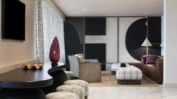 A modern living room with a dark-toned sofa, a round coffee table, and a patterned ottoman.