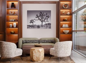 A modern living room with a sofa, two armchairs, a coffee table, and a wall-mounted shelf with decorative items. - Hotel Solaya, part of JdV by Hyatt (Scottsdale)