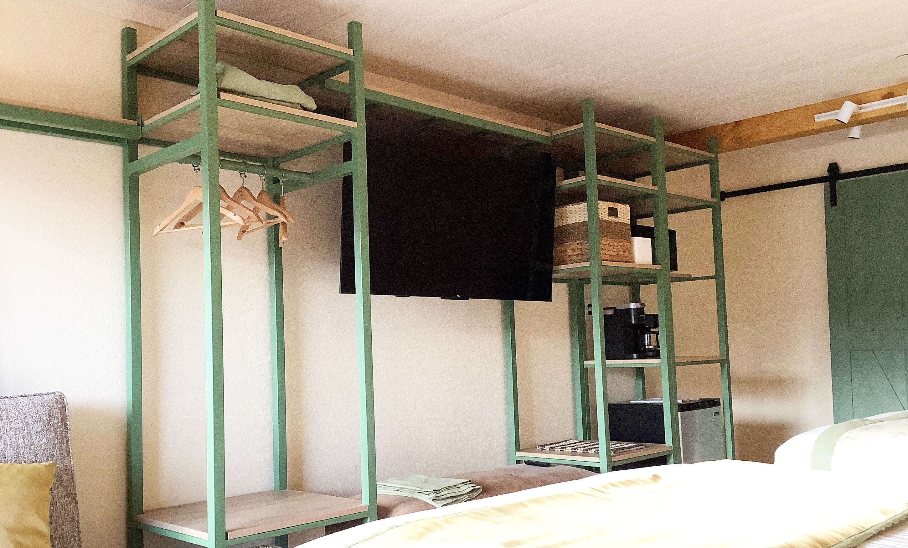 Ein Etagenbett mit grünem Metallgestell, ein kleiner Nachttisch und ein Kopfkissen.