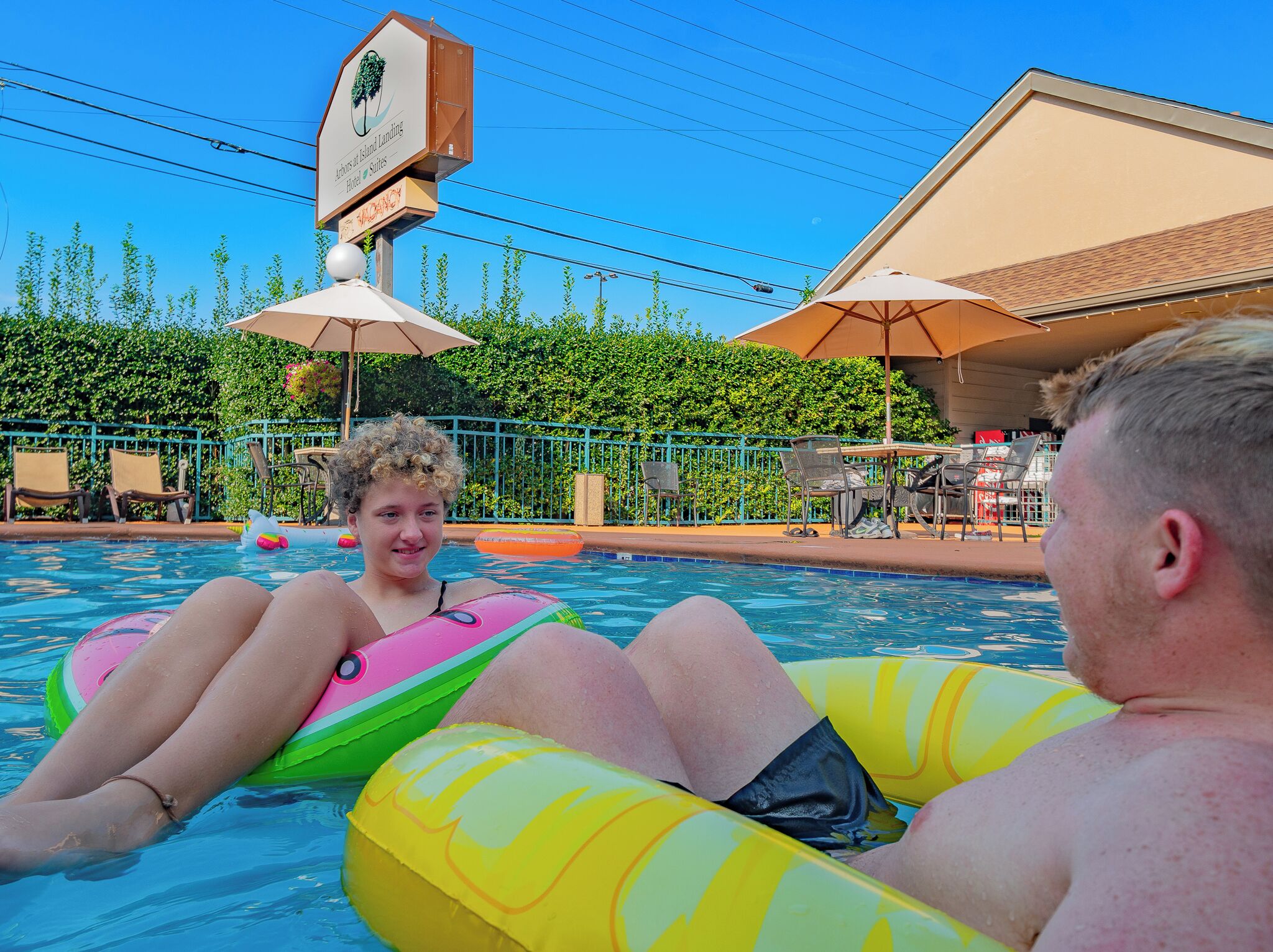 Zona de piscina con sillones y sombrillas.