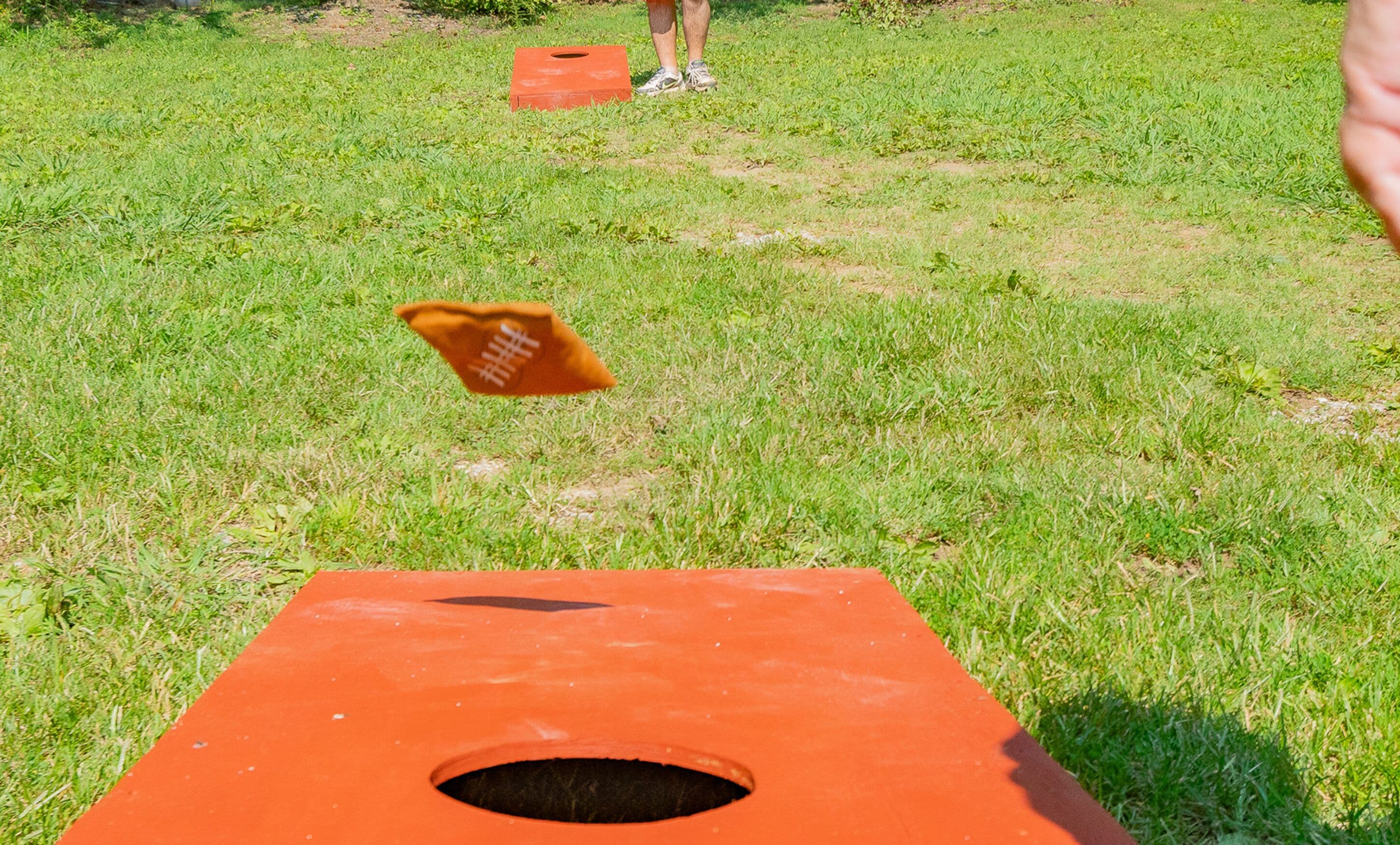 Une personne joue à un jeu sur un grand plateau orange, sur un terrain herbeux.