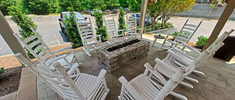 Une terrasse avec des chaises blanches et un foyer en pierre.