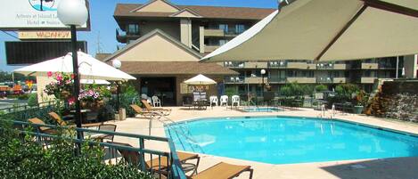 A hotel with a swimming pool, outdoor seating, and a sign indicating vacancies.