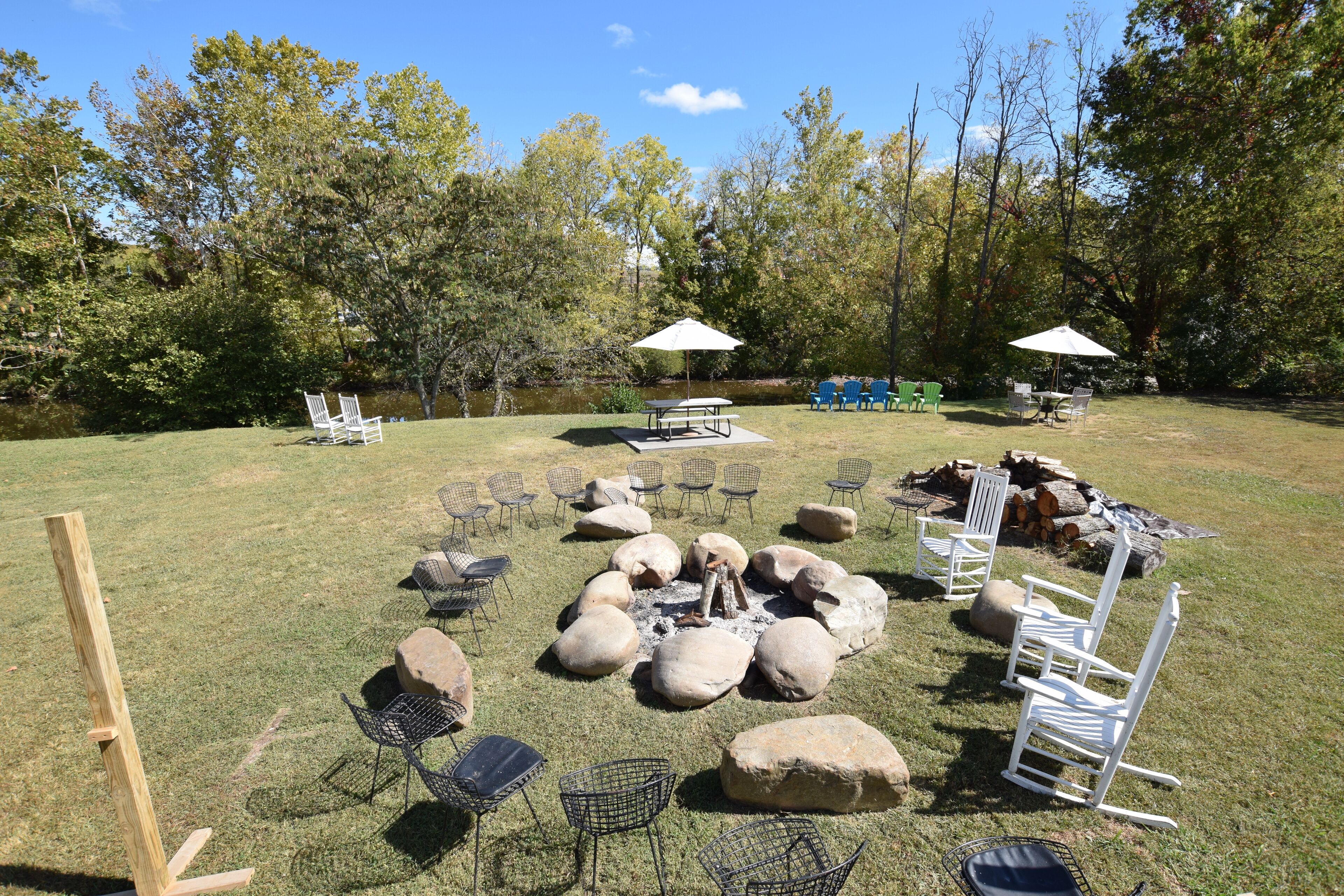 An outdoor seating area with tables, chairs, and a fire pit surrounded by rocks.