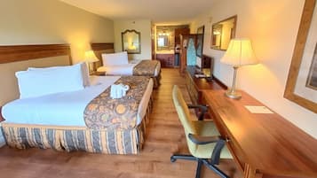 A hotel room with two beds, a desk, a chair, and a bathroom visible in the background.