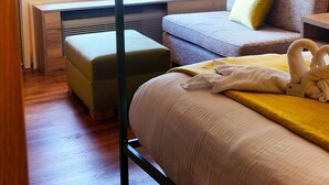 A bedroom with a bed, a sofa, a window with blinds, and a picture on the wall.