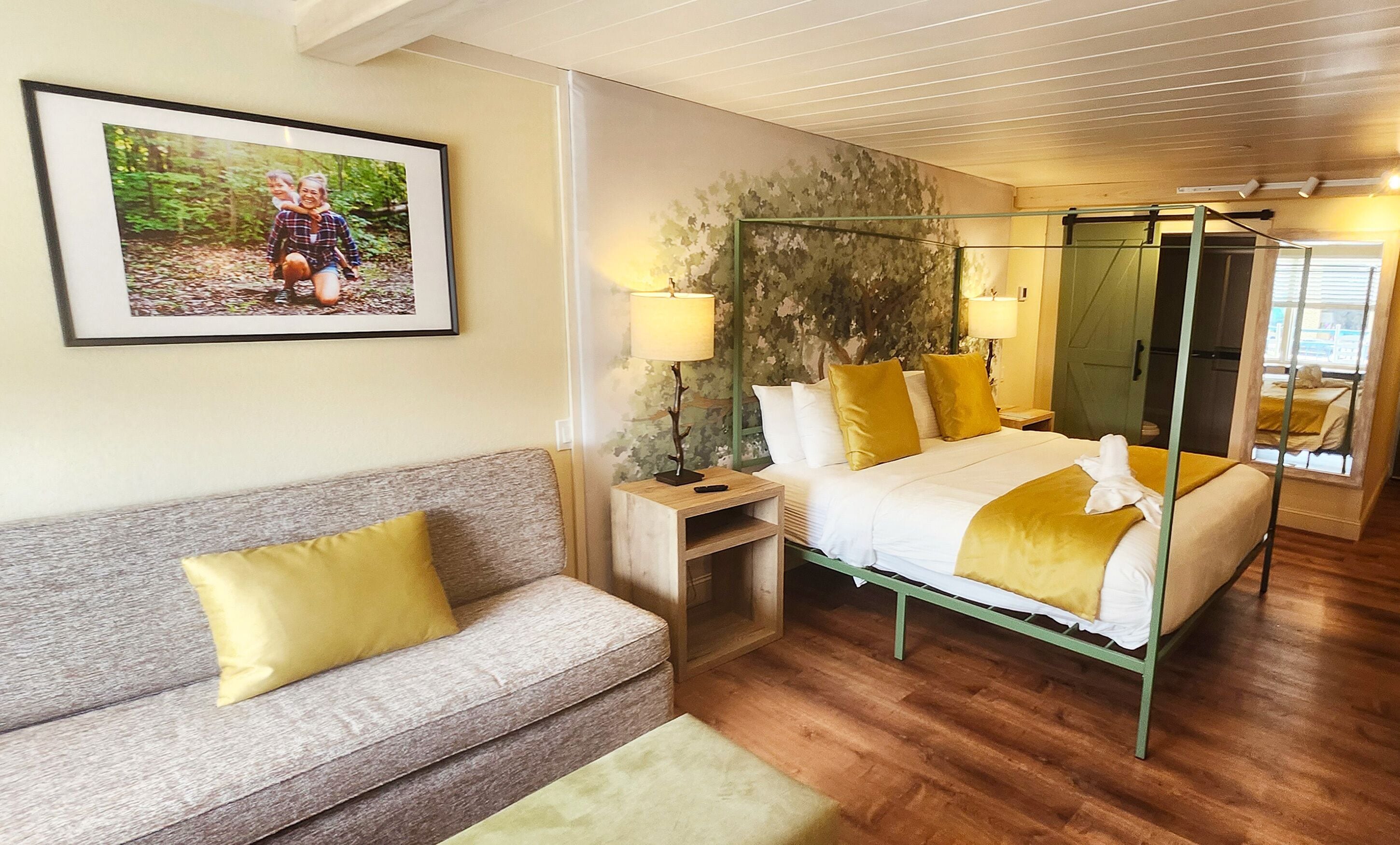 Ein Hotelzimmer mit Bett, Sofa, Nachttisch, Lampe und einem Bild an der Wand.