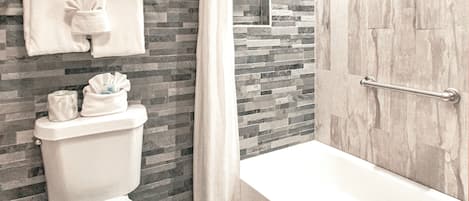 Een badkamer met een toilet, een douche en een bad.