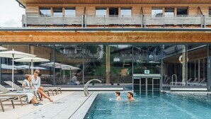 Ein modernes Gebäude mit Schwimmbecken, Liegestühlen und einer Glasfassade.