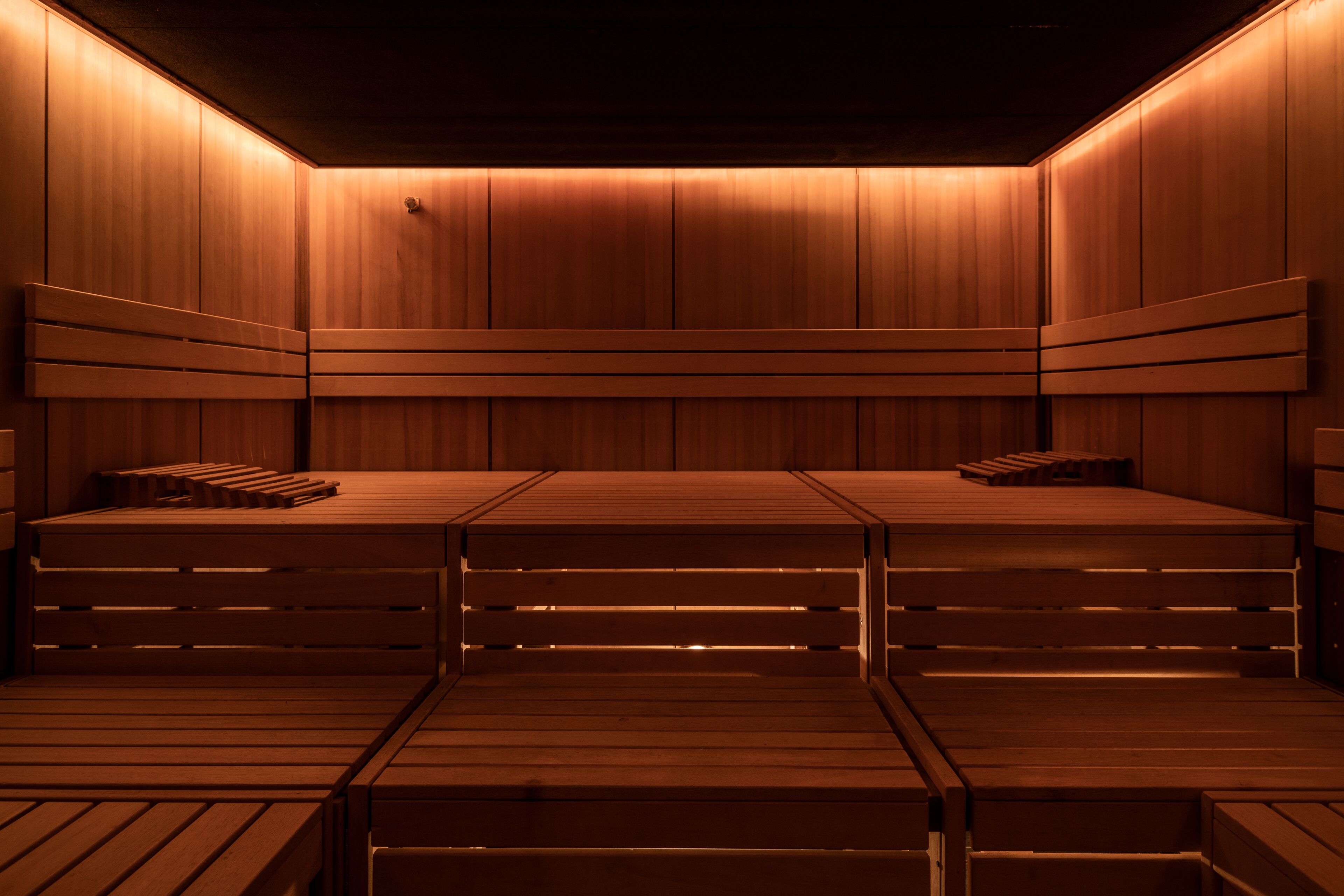 Uma sauna com bancos e paredes de madeira, com iluminação suave e acolhedora.
