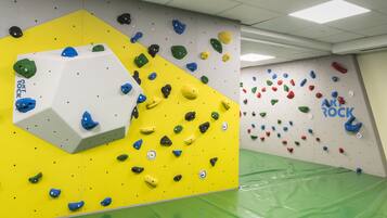 Une salle d’escalade dotée de prises de différentes couleurs et d’un grand mur d’escalade blanc.
