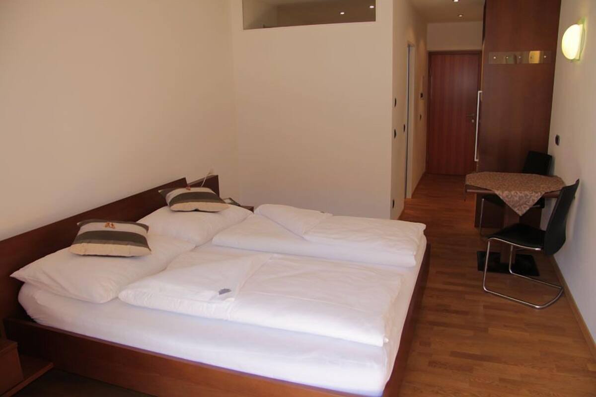 Hotellihuone, jossa on parivuode, pieni työpöytä tuolilla sekä puinen vaatekaappi.