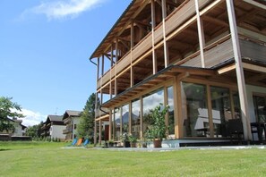 Un bâtiment moderne à deux étages, doté de grandes fenêtres en verre et de balcons en bois.