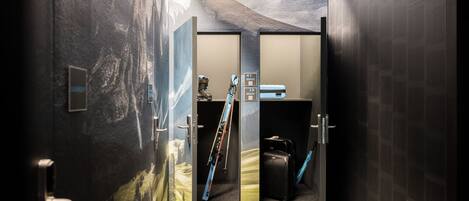 A hallway with a ski rack, a suitcase, and a wall with a mountain landscape mural.
