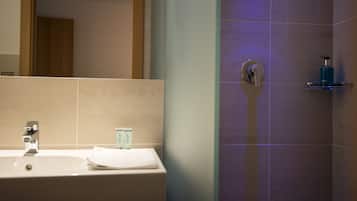 A bathroom with a sink, mirror, and shower area.