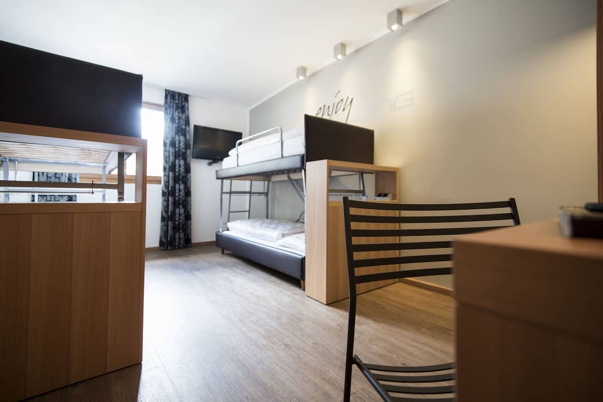 A compact room with a bunk bed, a desk, and a chair.