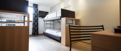 A compact room with a bunk bed, a desk, and a chair.