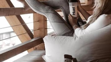 A person sitting on a wooden bench in a room with a sloped ceiling, holding a water bottle.