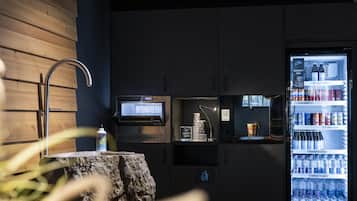 Una cocina moderna con refrigerador empotrado lleno de bebidas, un lavamanos y un microondas.