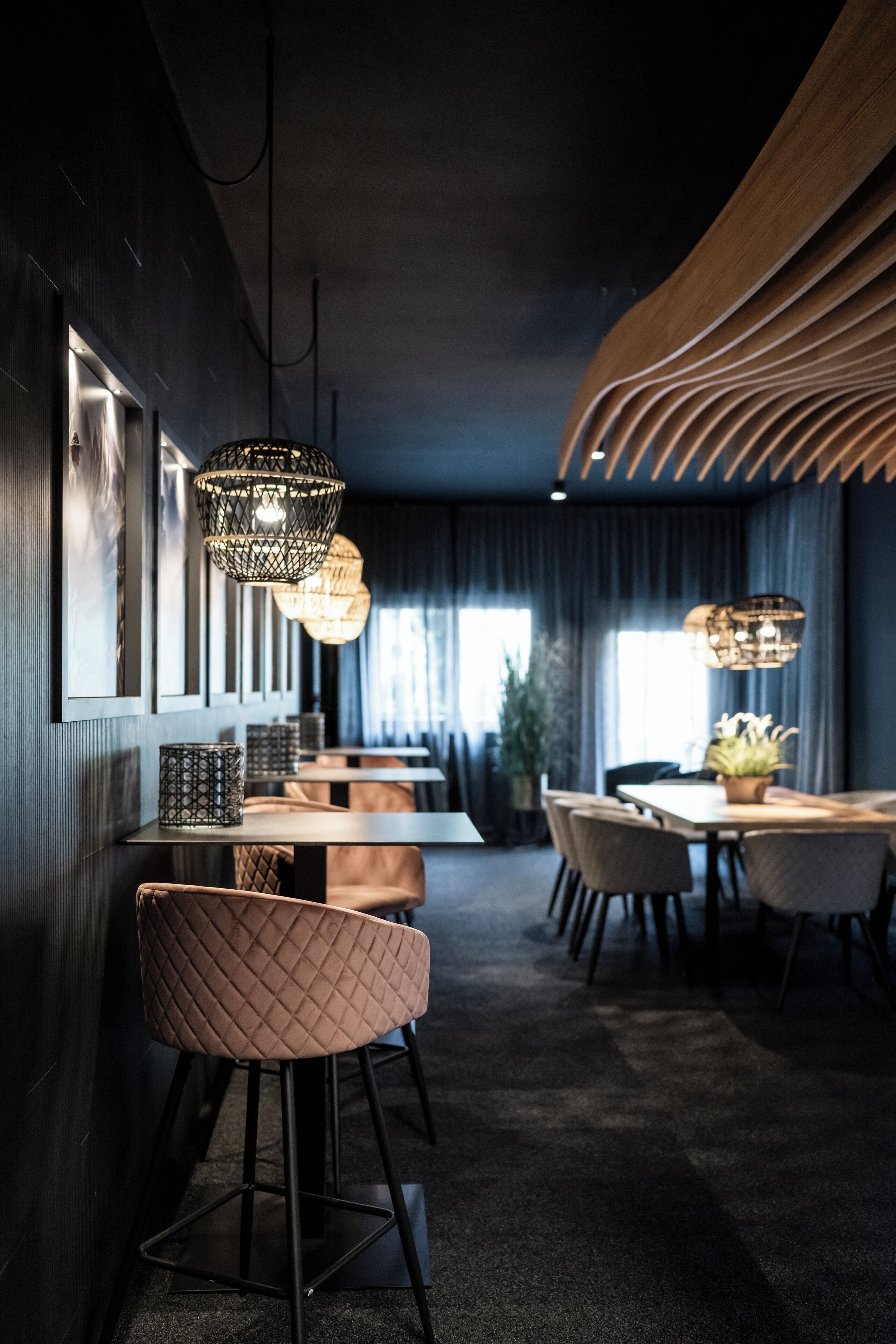 Un interior moderno con una larga mesa de comedor, varias sillas e iluminación colgante.