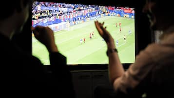 Un televisor mostrando un partido de fútbol con un público en el fondo.
