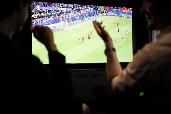 Un televisor mostrando un partido de fútbol con un público en el fondo.
