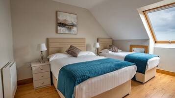 A bedroom with two beds, a nightstand, a radiator, and a window with a view.