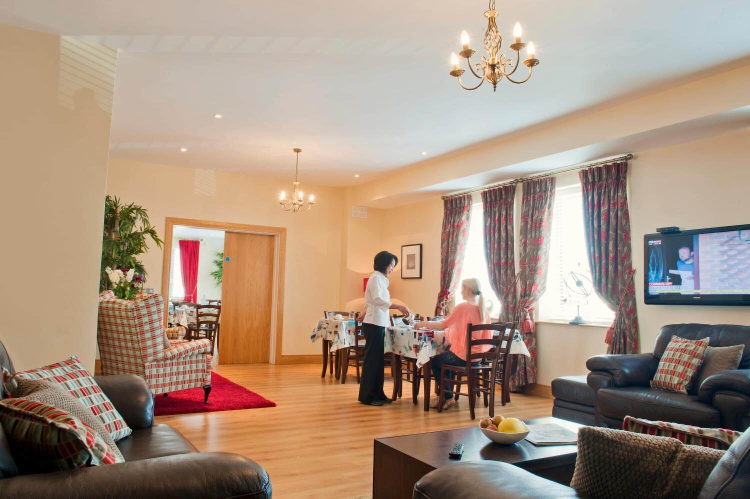A living room with a dining area, a chandelier, and a television.