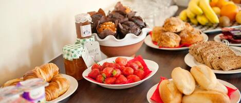 A breakfast buffet with various food items including pastries, fruits, and bread.