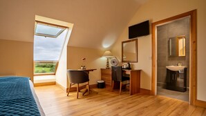 A bedroom with a skylight, a desk, a chair, a bed, a TV, and a bathroom with a mirror and sink. - Kinvara Guesthouse (Kinvara)