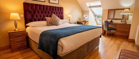 A bedroom with a large bed, two bedside tables with lamps, a desk, and a chair.