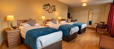 Una habitación de hotel con dos camas, pisos de madera, un escritorio, una silla y un espejo.
