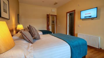 Een hotelkamer met een bed, een televisie waarop 'WELKOM' staat, een lamp en een deur naar een andere kamer.