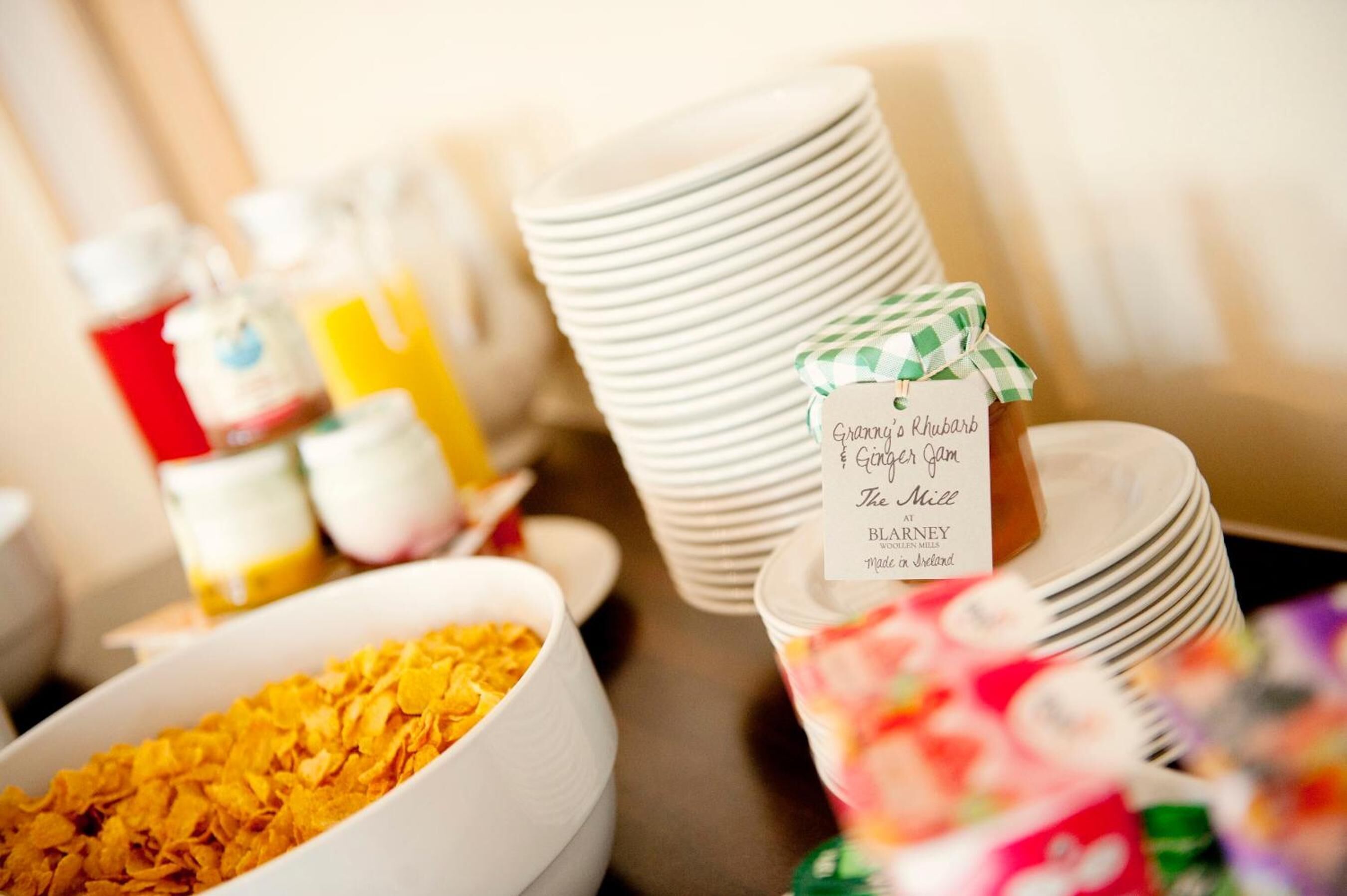 Un buffet de petit-déjeuner proposant une variété d’aliments et des assiettes blanches empilées.