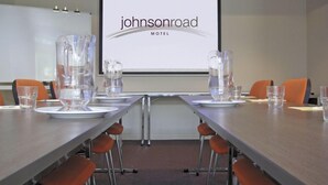 Une salle de conférence avec une longue table, des chaises et un écran de projection affichant le texte « Johnson Road Motel ».