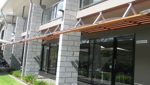 Un bâtiment moderne, avec une enseigne indiquant la présence d’un restaurant, de grandes fenêtres et un espace extérieur abrité avec des tables.
