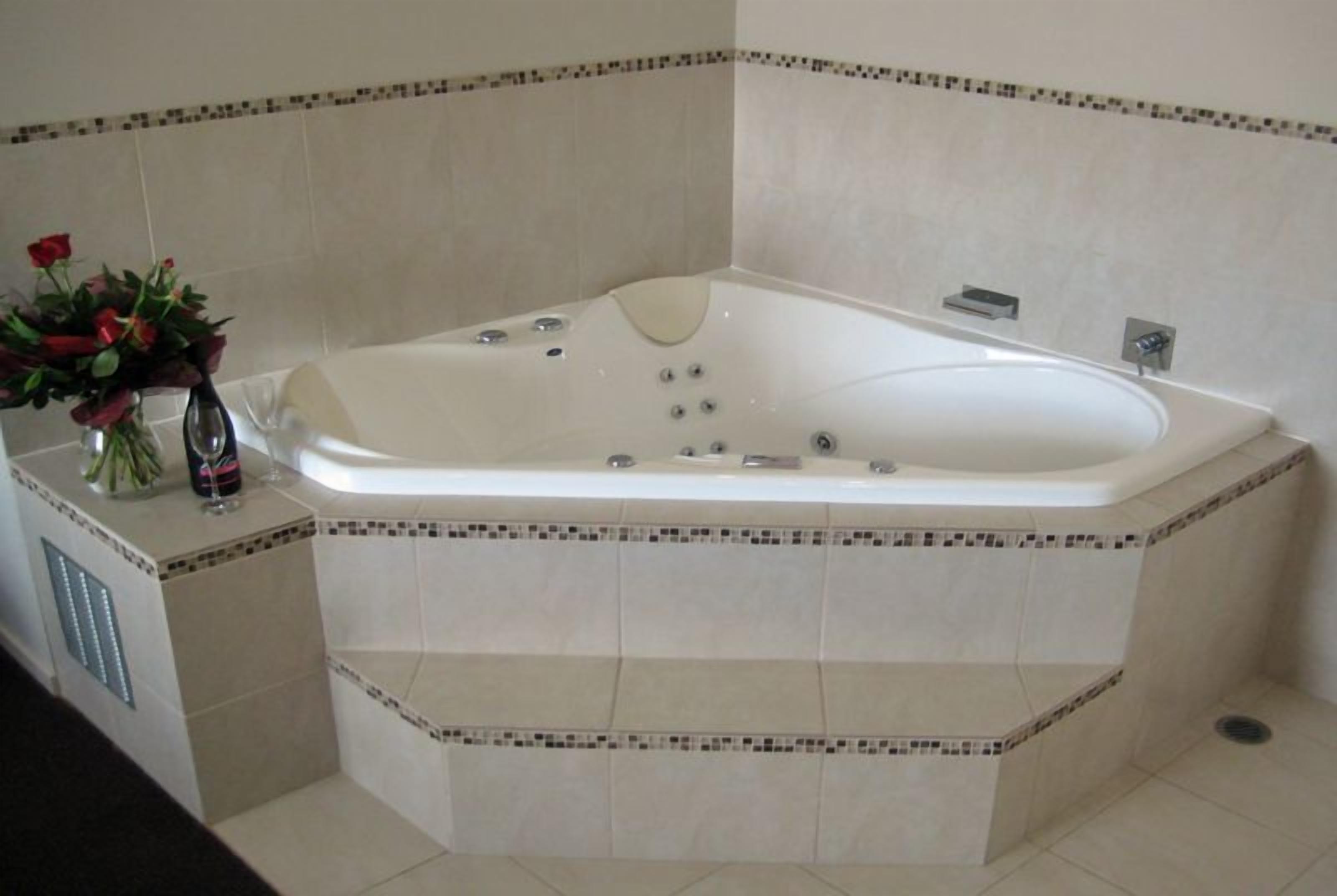 A large, freestanding bathtub in a bathroom with tiled walls and a decorative border.