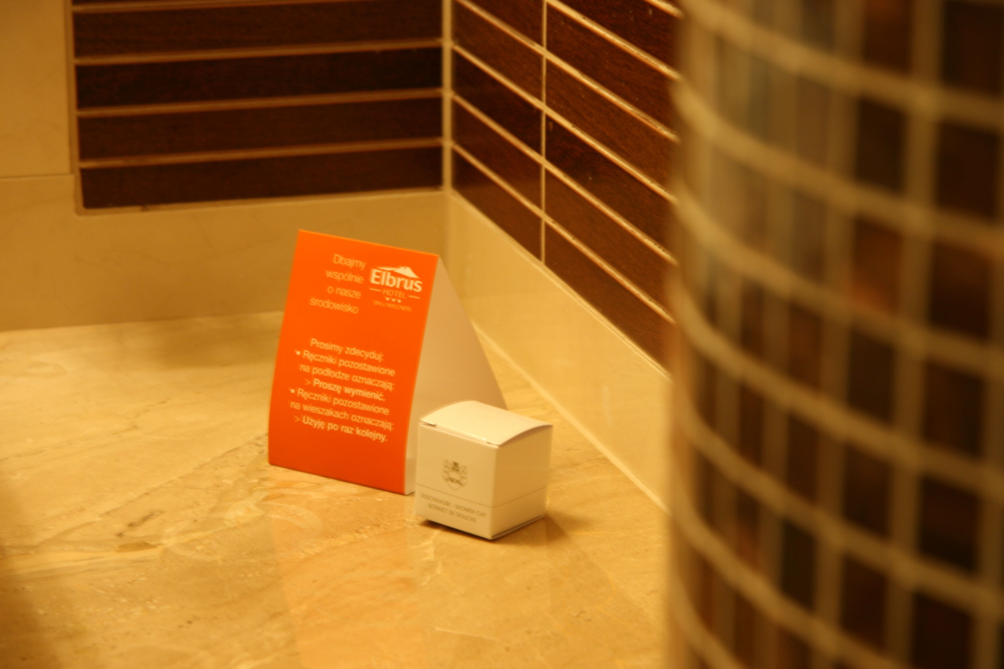 A tiled bathroom with a small white box and an orange sign.