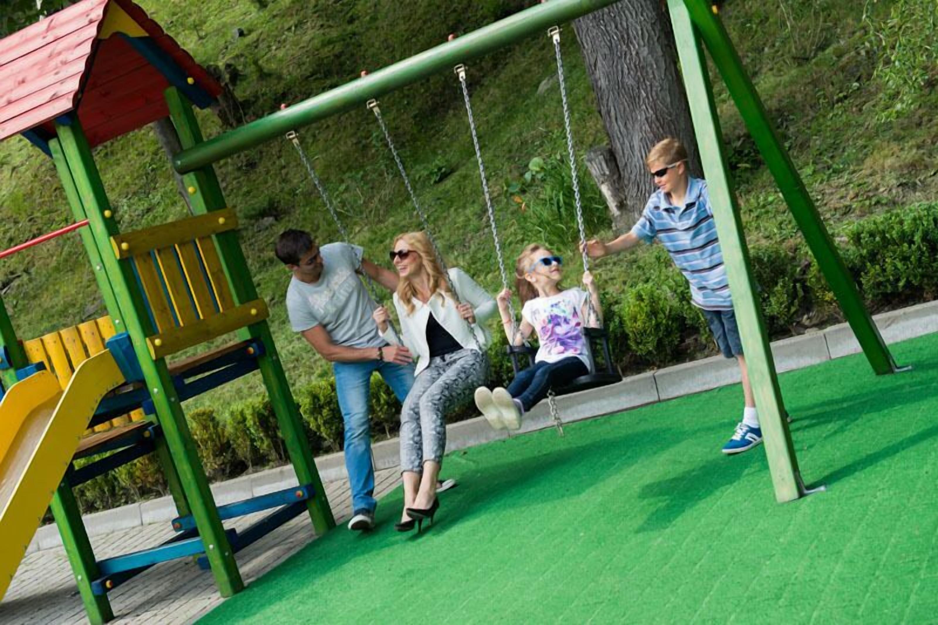 Un parque infantil con columpios, un tobogán y una estructura para escalar.