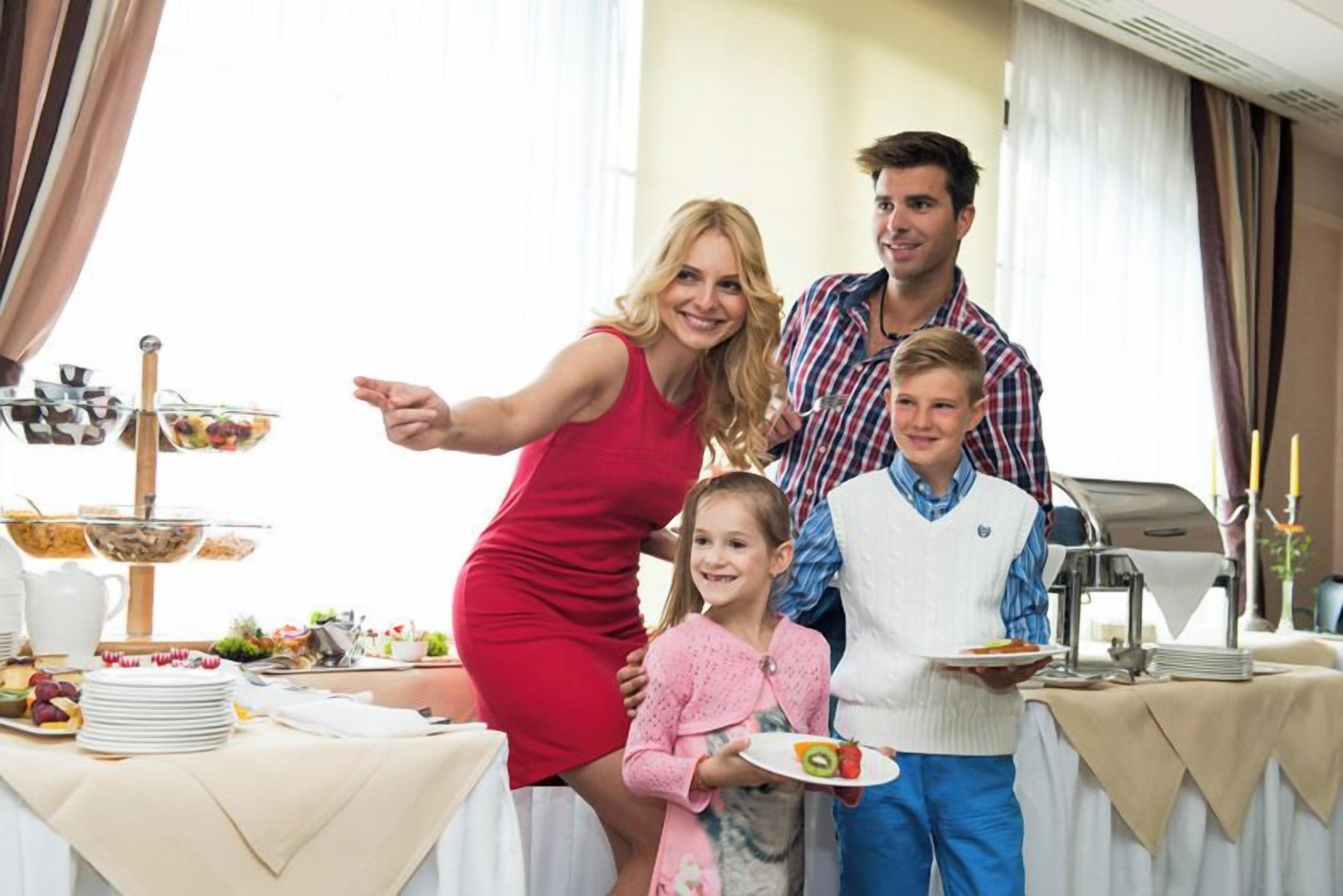 A family at a buffet table with various food items and a beverage pitcher.