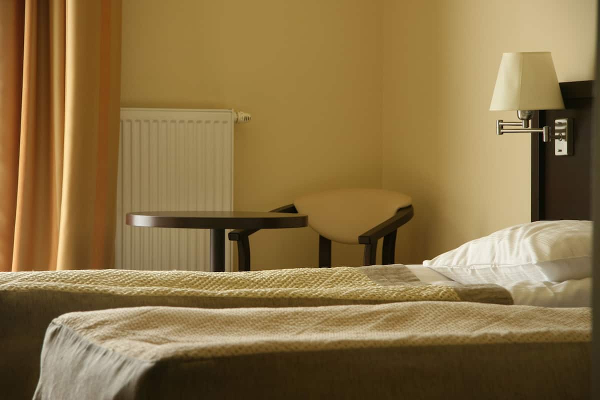 Una habitación de hotel con una cama, una silla, una mesa y una lámpara.
