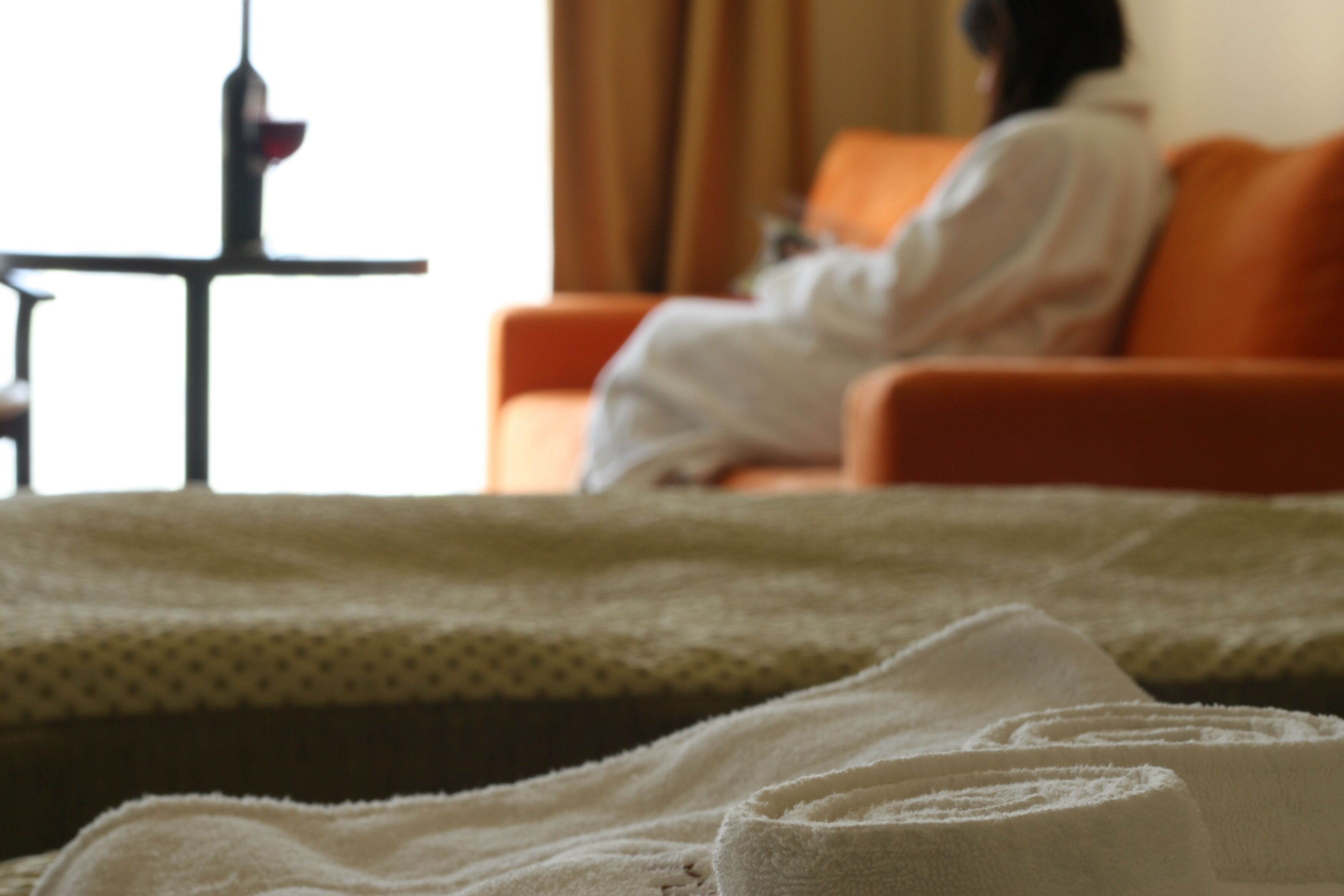 Una habitación de hotel con una cama, una silla y una mesa con un objeto rojo encima.