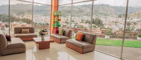 A spacious room with large windows offering a city view, a modern sofa set, and a colorful stack of blocks.