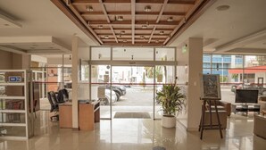 A reception area with a wooden ceiling, a reception desk, a potted plant, and a painting on easels. - Hotel Ambato (Ambato)