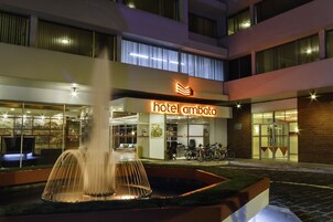 Entrada de hotel con una fuente, un letrero que dice "hotel ambato" y bicicletas estacionadas afuera.