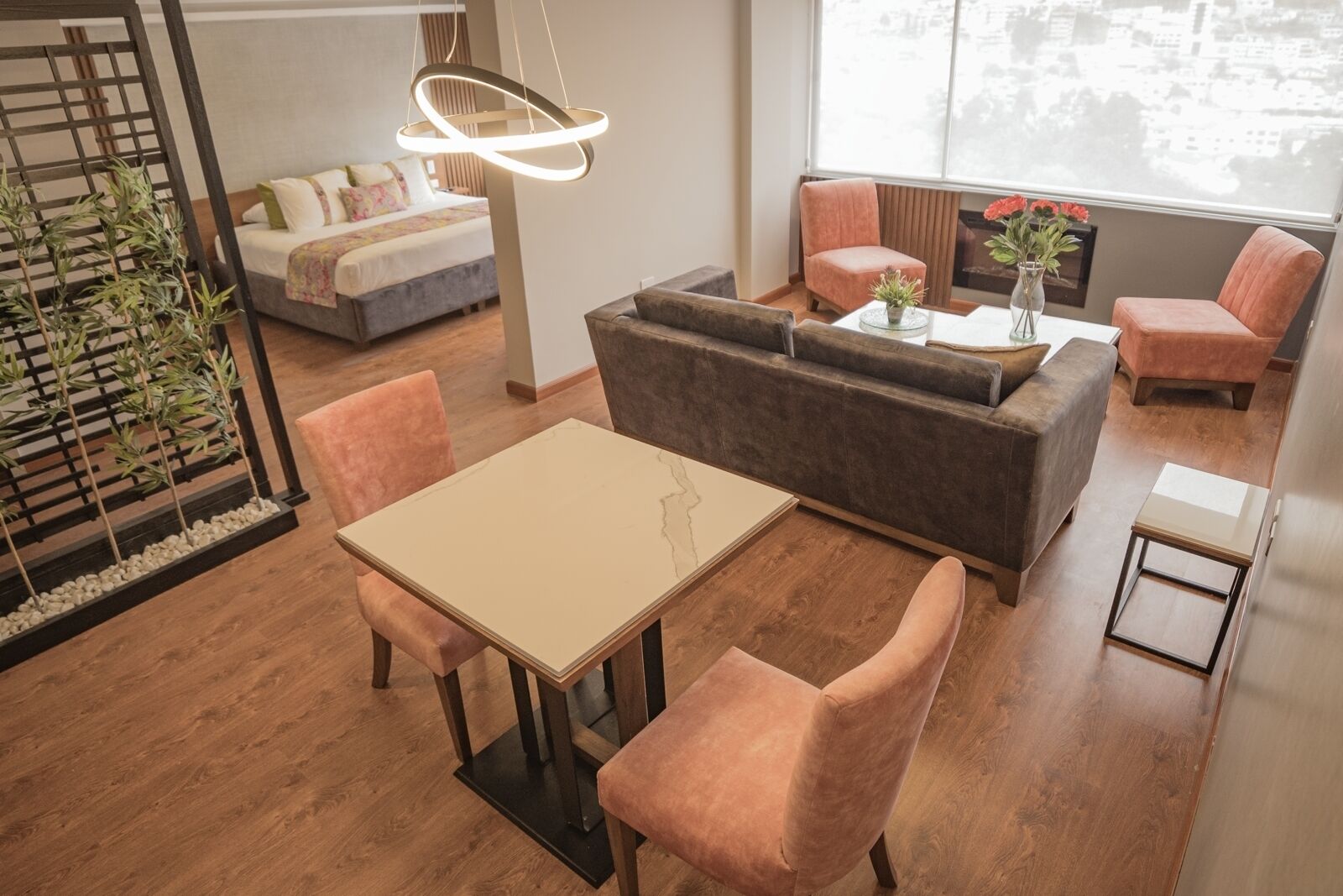 A modern living room with a sofa, a dining table, and chairs, a small coffee table, and a hanging light fixture.