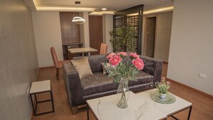 A modern living room with a grey sofa, a coffee table, and a dining area with a table and chairs. - Hotel Ambato (Ambato)