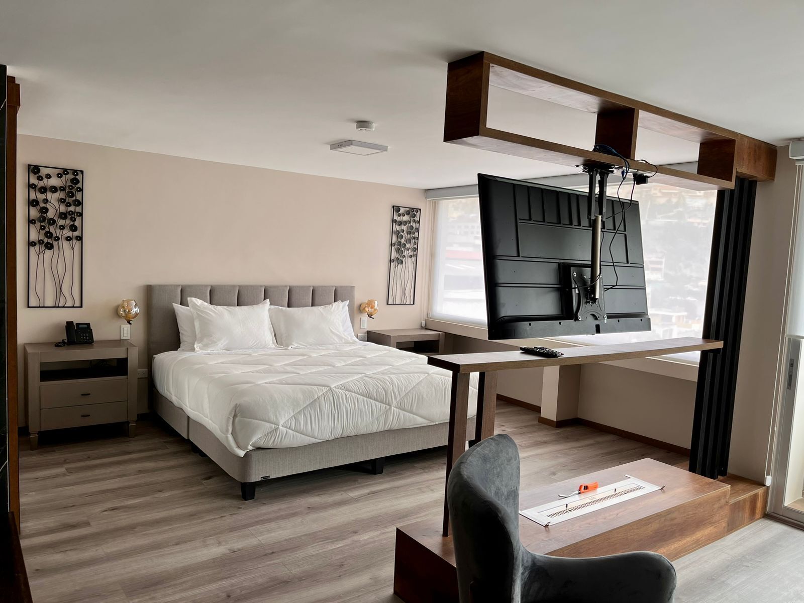 A modern bedroom with a bed, desk, chair, and artwork on the walls.