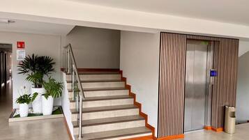 Ein modernes Interieur mit Treppe, einer vertikalen Wandverkleidung und einem Mülleimer.